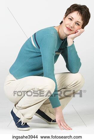 Crouching woman in casual attire smiling View Large Photo Image Picture - Crouching woman in casual attire smiling . Fotosearch
