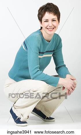 Crouching woman in casual attire smiling View Large Photo Image Stock Image - Crouching woman in casual attire smiling. Fotosearch