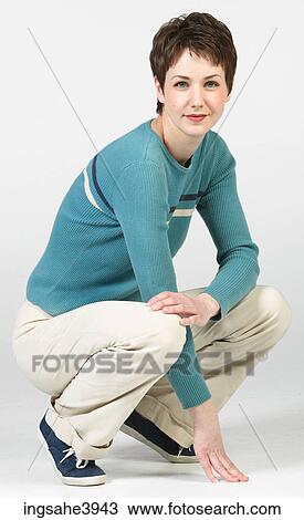 Stock Image - Crouching woman in casual attire. Fotosearch