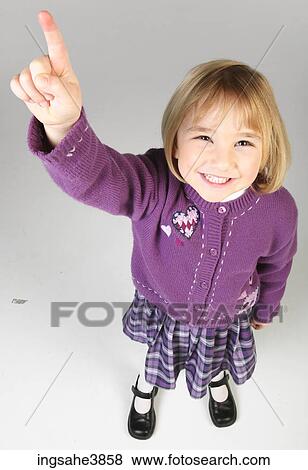 Stock Photo - Little girl in purple outfit pointing upwards and smiling. Fotosearch