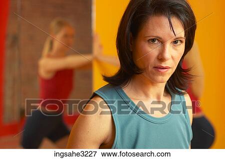 Mature adult woman lifting weights with woman stretching in background View Large Photo Image Stock Photo - Mature adult woman lifting weights with woman stretching in background . Fotosearch