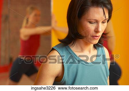 Mature adult woman lifting weights with woman stretching in background View Large Photo Image Stock Photograph - Mature adult woman lifting weights with woman stretching in background . Fotosearch