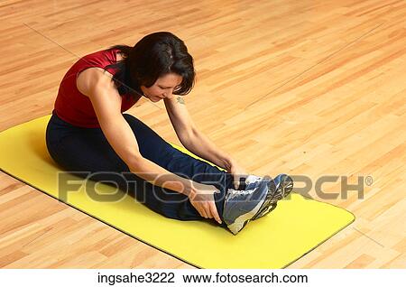 Stock Image - Mature adult woman stretching on exercise mat . Fotosearch
