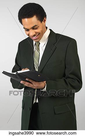 Smiling businessman writing in day planner View Large Photo Image Stock Image - Smiling businessman writing in day planner . Fotosearch