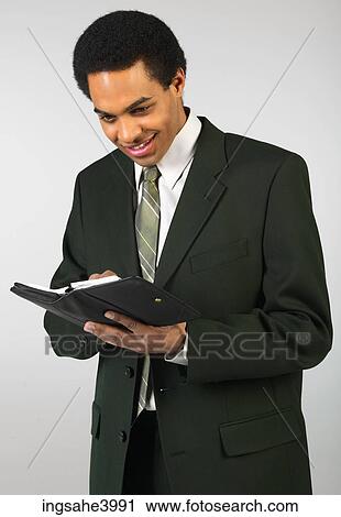 Smiling businessman writing in day planner View Large Photo Image Stock Image - Smiling businessman writing in day planner . Fotosearch