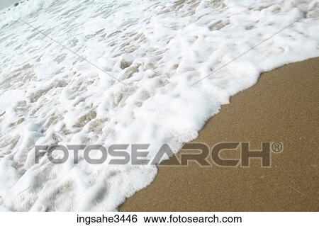 Stock Photograph - Wave and foam on beach . Fotosearch