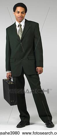 Young man standing and carrying a briefcase View Large Photo Image Stock Image - Young man standing and carrying a briefcase. Fotosearch