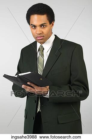 Stock Photo - Young man standing and writing in a organizer. Fotosearch