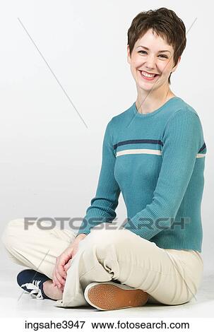 Young woman sitting cross legged on the floor and smiling View Large Photo Image Stock Photo - Young woman sitting cross legged on the floor and smiling . Fotosearch