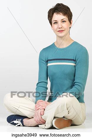 Young woman sitting cross legged on the floor and smiling View Large Photo Image Stock Photo - Young woman sitting cross legged on the floor and smiling . Fotosearch