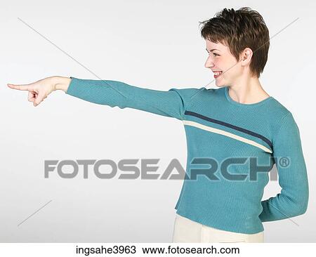 Young woman smiling and pointing towards an object View Large Photo Image Stock Image - Young woman smiling and pointing towards an object. Fotosearch