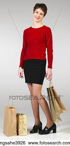 Young woman smiling and posing with shopping bags View Large Photo Image Stock Photograph - Young woman smiling and posing with shopping bags . Fotosearch