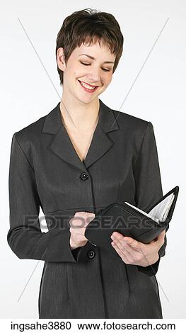 Young woman smiling and reading from a organizer View Large Photo Image Stock Image - Young woman smiling and reading from a organizer. Fotosearch