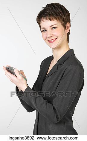 Young woman smiling while using a palm held computing device View Large Photo Image Stock Image - Young woman smiling while using a palm held computing device. Fotosearch