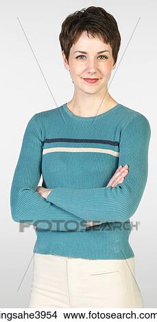 Young woman standing with her arms folded and smiling View Large Photo Image Picture - Young woman standing with her arms folded and smiling. Fotosearch
