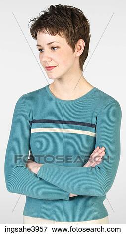 Young woman standing with her arms folded View Large Photo Image Stock Photo - Young woman standing with her arms folded. Fotosearch