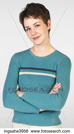 Young woman standing with her arms folded and smiling View Large Photo Image Stock Photograph - Young woman standing with her arms folded and smiling . Fotosearch