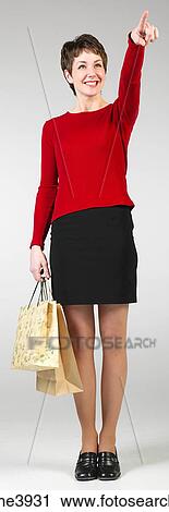 Young woman standing with shopping bags and pointing towards an object View Large Photo Image Stock Image - Young woman standing with shopping bags and pointing towards an object . Fotosearch