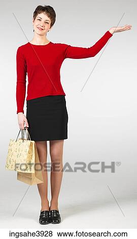 Young woman standing with shopping bags and pointing towards an object View Large Photo Image Stock Photo - Young woman standing with shopping bags and pointing towards an object . Fotosearch