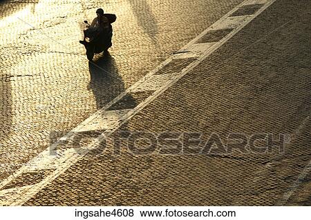 Aerial view of person riding scooter on empty street View Large Photo Image Stock Photo - Aerial view of person riding scooter on empty street . Fotosearch
