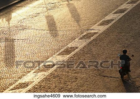 Aerial view of person riding scooter on empty street View Large Photo Image Stock Photo - Aerial view of person riding scooter on empty street . Fotosearch