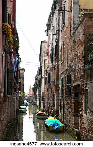 Boats moored to side of building in Venetian canal View Large Photo Image Stock Photo - Boats moored to side of building in Venetian canal . Fotosearch