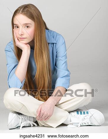Stock Image - Bored teenaged girl sitting cross-legged. Fotosearch