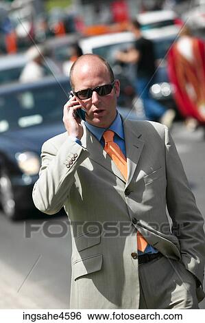 Stock Photograph - Businessman in gray suit and sunglasses talking on cell phone . Fotosearch