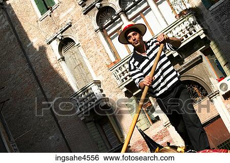 Gondolier steering gondola on sunny canal in Venice View Large Photo Image Stock Photograph - Gondolier steering gondola on sunny canal in Venice . Fotosearch