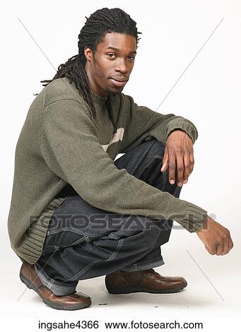 Kneeling man with dreadlocks in jeans and sweater View Large Photo Image Stock Photograph - Kneeling man with dreadlocks in jeans and sweater. Fotosearch