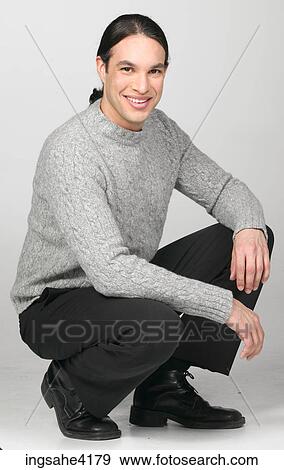 Man in gray sweater smiling and crouching on the floor View Large Photo Image Stock Photo - Man in gray sweater smiling and crouching on the floor . Fotosearch