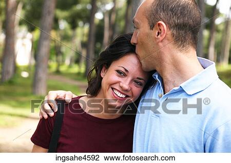 Man kissing smiling girlfriend in park View Large Photo Image Stock Image - Man kissing smiling girlfriend in park . Fotosearch