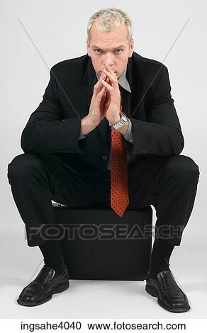 Stock Image - Man seated on a briefcase . Fotosearch