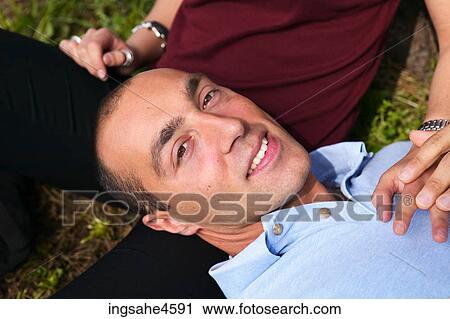 Stock Image - Man's smiling face resting on woman's leg . Fotosearch