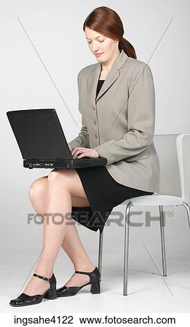 Seated businesswoman typing on black laptop View Large Photo Image Stock Image - Seated businesswoman typing on black laptop. Fotosearch
