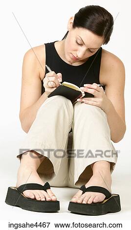 Seated young woman in casual attire writing in book View Large Photo Image Stock Photo - Seated young woman in casual attire writing in book. Fotosearch