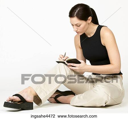 Seated young woman writing in book View Large Photo Image Stock Image - Seated young woman writing in book. Fotosearch