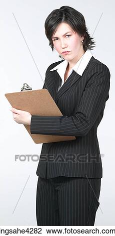 Stock Image - Serious businesswoman in suit writing on clipboard. Fotosearch