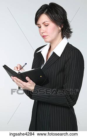 Serious businesswoman writing in organizer View Large Photo Image Picture - Serious businesswoman writing in organizer. Fotosearch