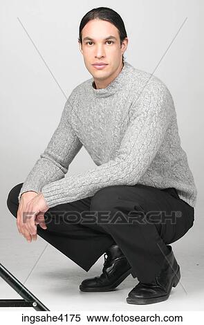 Serious man in gray sweater crouching on the floor View Large Photo Image Stock Photography - Serious man in gray sweater crouching on the floor. Fotosearch