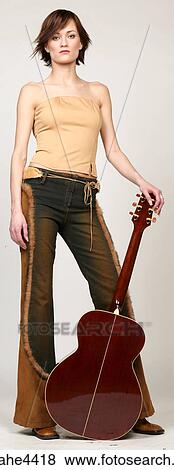 Stock Photo - Serious woman leaning on acoustic guitar. Fotosearch