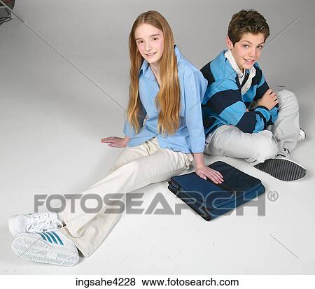 Stock Photo - Smiling boy and girl sitting beside school book. Fotosearch