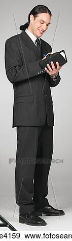 Smiling businessman in gray suit writing in organizer View Large Photo Image Stock Photo - Smiling businessman in gray suit writing in organizer . Fotosearch