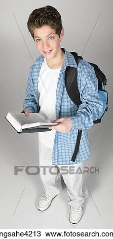 Stock Image - Smiling teenaged boy carrying book bag and textbook. Fotosearch