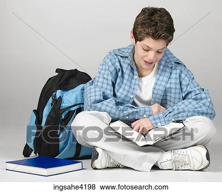 Smiling teenaged boy studying from textbook View Large Photo Image Stock Photo - Smiling teenaged boy studying from textbook. Fotosearch