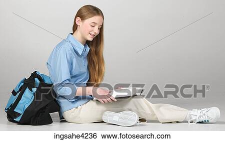 Stock Photograph - Smiling teenaged girl studying from textbook. Fotosearch