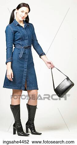 Smiling woman in denim dress with black purse View Large Photo Image Stock Image - Smiling woman in denim dress with black purse. Fotosearch