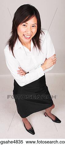Smiling young Asian business woman standing with her arms crossed in front of her View Large Photo Image Stock Photography - Smiling young Asian business woman standing with her arms crossed in front of her. Fotosearch