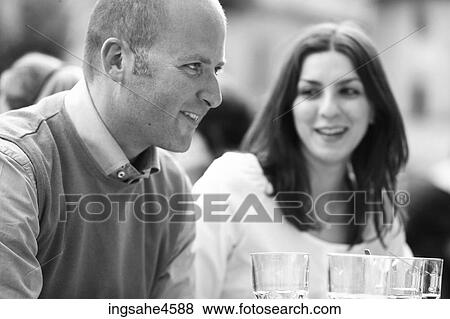Stock Photo - Smiling young couple having drinks on a patio . Fotosearch