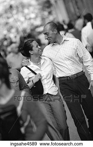 Stock Photo - Smiling young couple walking down busy city street . Fotosearch